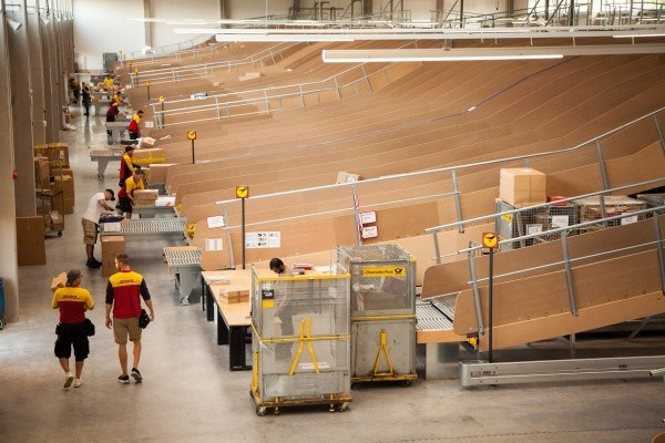  Deutsche Post DHL Group: Neue mechanisierte Zustellbasis in Berlin-Pankow wird in Betrieb genommen: Rutschen, Paketzusteller bei Beladung - Foto: Deutsche Post DHL