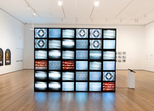 Adrian Piper, Mauer, 2010. Video Installation: Fernsehmonitore, Videos mit zufällig pro- grammierten Bildern, frische Rosen. Format variabel. Installa- tionsansicht: Adrian Piper: A Synthesis of Intuitions, 1965- 2016, Museum of Modern Art, New York, März-Juli 2018. Sammlung Adrian Piper Research Archive Foundation Berlin